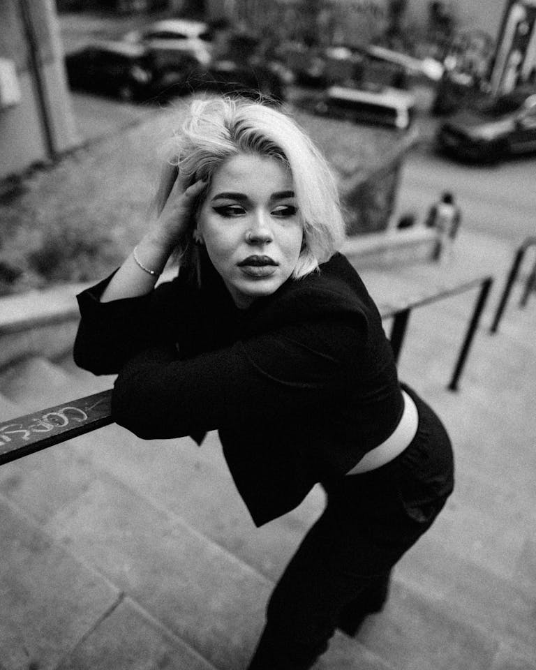 Stylish black and white portrait of a woman posing on urban stairs with a dramatic tone.